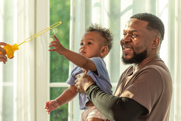 Happy african black parents dad father throw baby son on piggyback and neck riding teasing fun near...