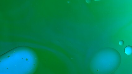 Clean oil drops floating and mixing on ink green colored water surface, abstract background, wallpaper template.