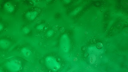 Blurred oil drops floating on beautiful green water surface, abstract background, wallpaper template.