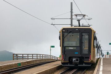 Fototapeta premium Train on the end station Rigi Kulm on the top of a mountain in a foggy morning