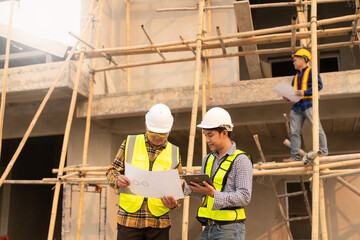 Co-workers discussing architecture projects at construction site at table Architects work with Engineer inspects site for construction project draft, architectural plan