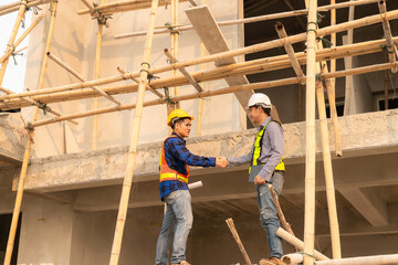 Fototapeta na wymiar Architect and construction engineer holding hands while working for teamwork and cooperation concept after completing an agreement on construction site.