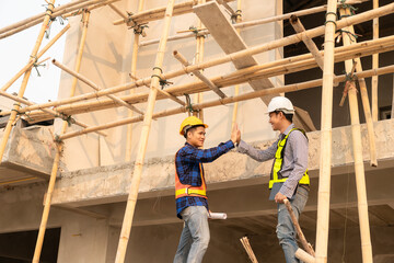 Naklejka na ściany i meble Architect and construction engineer holding hands while working for teamwork and cooperation concept after completing an agreement on construction site.