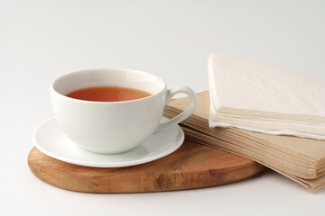 Cup of tea and paper napkin on white background