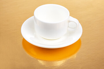 white coffee cup with saucer on golden background