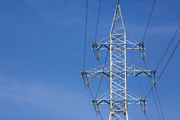 Electrical tower with voltage transmission wires against the background of blue sky. High voltage...