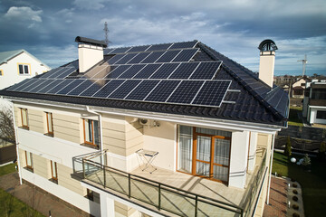 Obraz premium Home residence with solar panel system for generating electricity through photovoltaic effect. Aerial view of two-storey house with solar modules on roof. Ecological renewable energy sources concept.