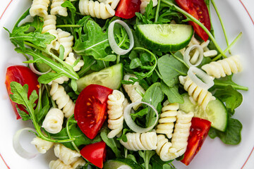 pasta salad fusilli pasta, cucumber, tomato, green lettuce, onion healthy eating cooking appetizer meal food snack on the table copy space food background rustic top view