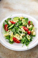 pasta salad fusilli pasta, cucumber, tomato, green lettuce, onion healthy eating cooking appetizer meal food snack on the table copy space food background rustic top view