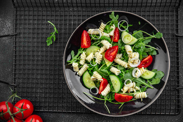 pasta salad fusilli pasta, cucumber, tomato, green lettuce, onion healthy eating cooking appetizer meal food snack on the table copy space food background rustic top view