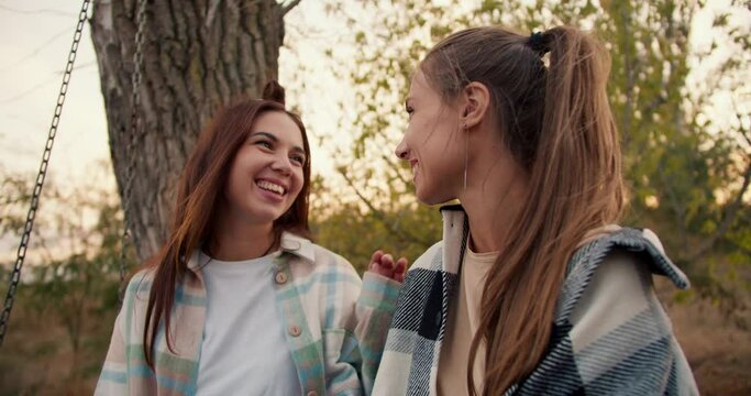Close-up shooting: Two girlfriends in checkered shirts hug and look into the distance. Rest in the country house