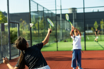 Happy sporty elementary school age girl, child playing badminton, holding a racket making funny faces, portrait, lifestyle. Sports, exercise and healthy outdoor activities leisure concept, one person
