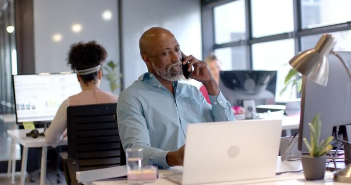 African american businessman using smartphone and laptop in office with copy space