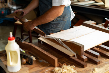 Guitar luthier ties rope, drives wedge to join spruce boards