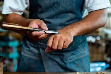 Closeup of Carpenter's Hand Sharpening Chisel