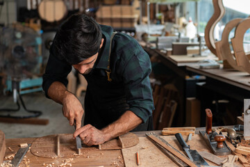 guitar luthier using chisel to shave bracing of acoustic guitar