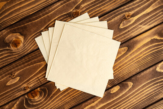 Stack of paper square napkins on brown wooden background