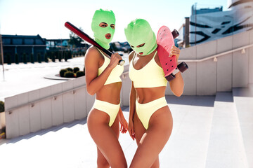 Two beautiful sexy women in green underwear. Models wearing bandit balaclava mask. Hot seductive...