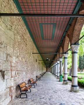 Long covered paved walkway with columns and benches. The walkway is located in the courtyard of Topkapi Palace, a former royal palace in Istanbul, Turkey