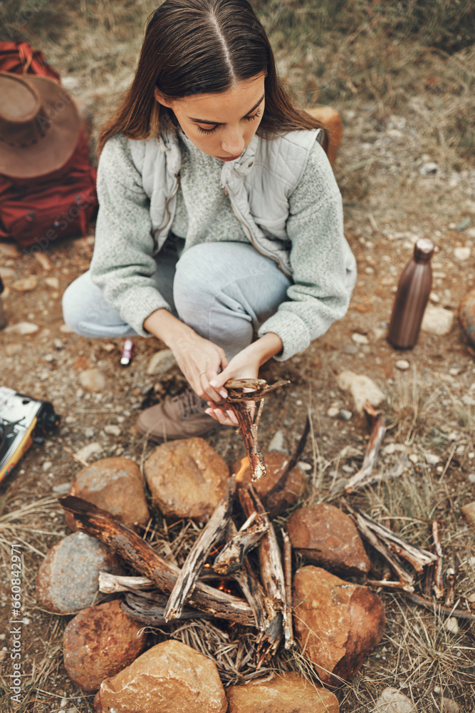 Wall mural Wood, nature and woman with fire on a camp on a mountain for adventure, weekend trip or vacation. Stone, sticks and young female person making a flame or spark in outdoor woods or forest for holiday.