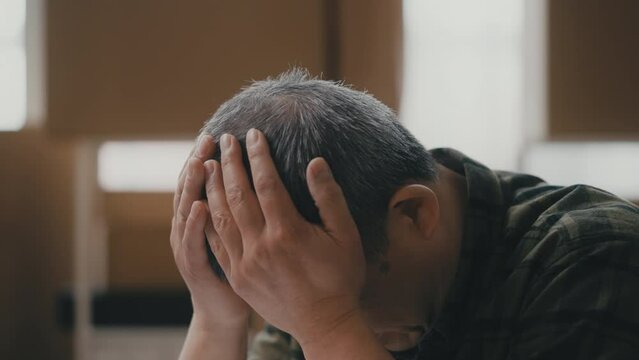 Senior Asian man feeling upset in his workshop, slow business, loss of clients