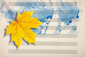 Melody concept. Old music sheet in blue watercolor paint and yellow fallen maple leaf. Music...