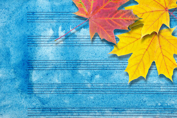 Melody concept. Old music sheet in blue watercolor paint and fallen maple leaves. Music concept. Abstract colorful watercolor background. Autumn melody