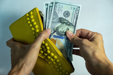 A woman hand take hundred dollars cash from a yellow purse