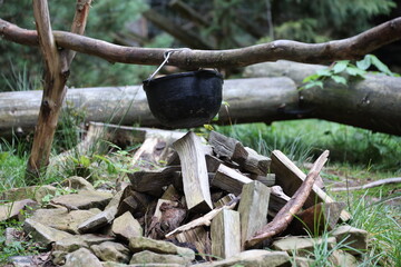 Tourist pot hanging over the fire on a tripod. Cooking in the campaign