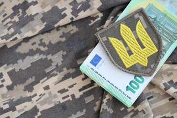 Ukrainian army symbol and bunch of euro bills on military uniform. Payments to soldiers of the Ukrainian army from European union, salaries to the military. War support