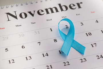 Closeup emblem of prostate cancer awareness - blue ribbon on November calendar background....
