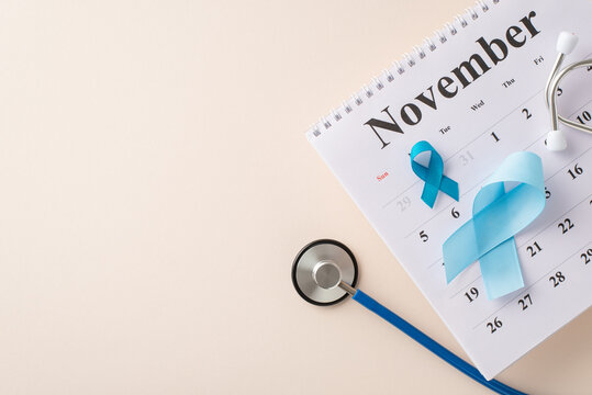 Man health month symbolism. Top view image featuring prostate cancer emblems - blue ribbons, November calendar, and a stethoscope for planned checkups on pastel beige with text room