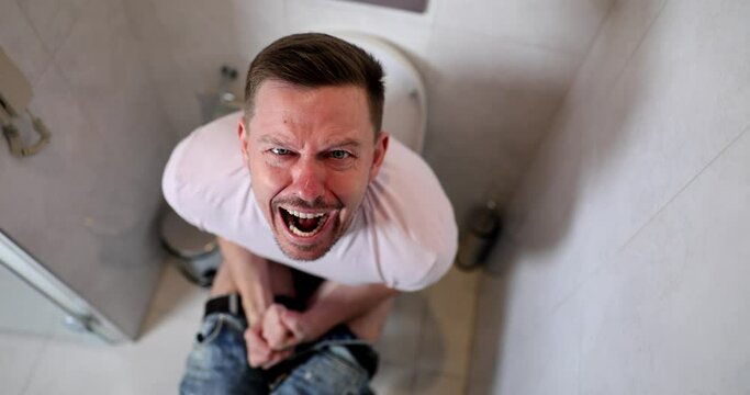 Man suffers from diarrhea constipation hemorrhoids sitting on toilet at home. Emotion pain digestive problem
