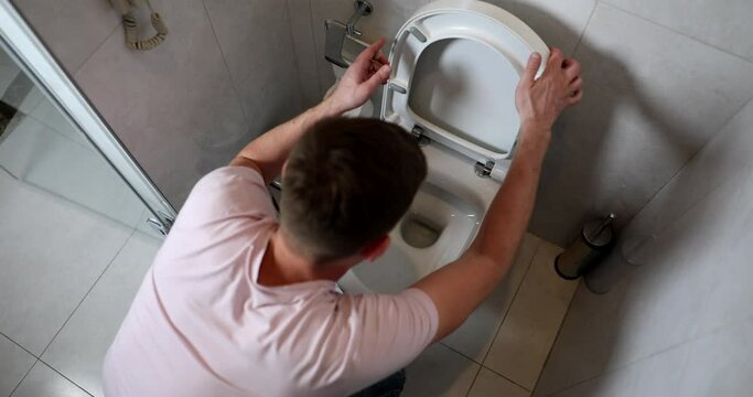 Man on his knees in bathroom vomits into toilet. Food poisoning food poisoning and rotavirus infection