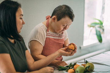Lifestyle, education. An elderly woman with Down syndrome tries her cooked food in class with a teacher