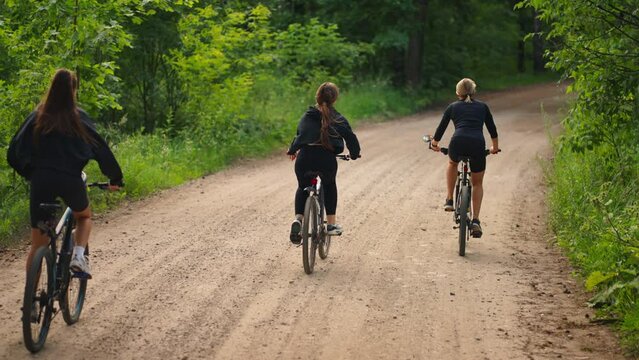 Teen Girls Riding Bikes In Forest, Back View, Following Shot, Slowmotion, Sport And Active Lifestyle