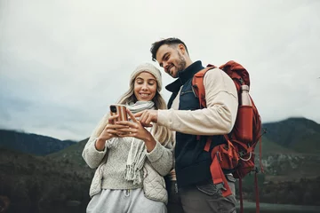Foto op Canvas Couple, phone and travel in nature or mountains with hiking information, social media or check for direction on journey. Happy people trekking in backpack, mobile chat or search for outdoor location © Rene L/peopleimages.com