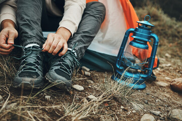 Shoes, hands tie shoelace and camping, person outdoor in nature for travel and adventure, explore...