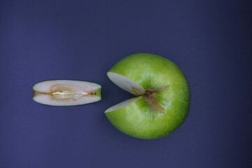 sliced green granny apple with a piece on a black background top view