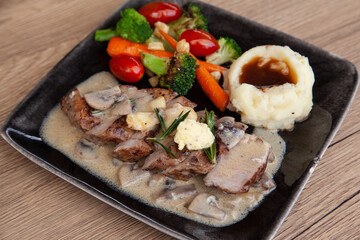 Pork shoulder steak with mushroom sauce, mashed potatoes and grilled vegetable