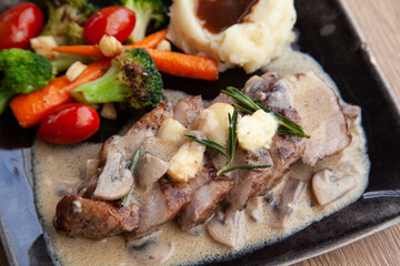 Pork shoulder steak with mushroom sauce, mashed potatoes and grilled vegetable