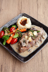 Pork shoulder steak with mushroom sauce, mashed potatoes and grilled vegetable