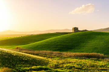 amazing sunset among green spring hills in highland farm with castle , mountains and picturesque colorful sunset on background of landscape