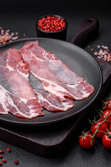 Slices of delicious smoked jamon or prosciutto with salt, spices and herbs