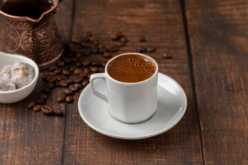 Turkish coffee in classic coffee cup with water and Turkish delight on wooden table
