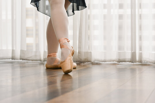 Close up classic ballerina legs in pointe shoes on the wooden floor. Dance, art and active lifestyle concept