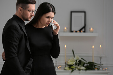 Sad couple mourning indoors, space for text. Funeral ceremony
