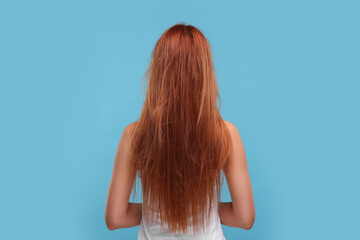 Naklejka premium Woman with damaged messy hair on light blue background, back view