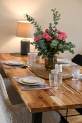 Beautiful table setting with bouquet and candles indoors. Roses and eucalyptus branches in vase