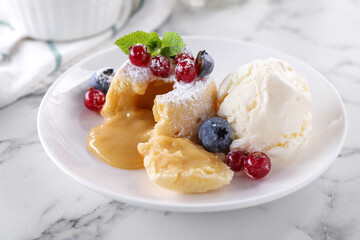 Tasty vanilla fondant with white chocolate, berries and ice cream on white marble table, closeup